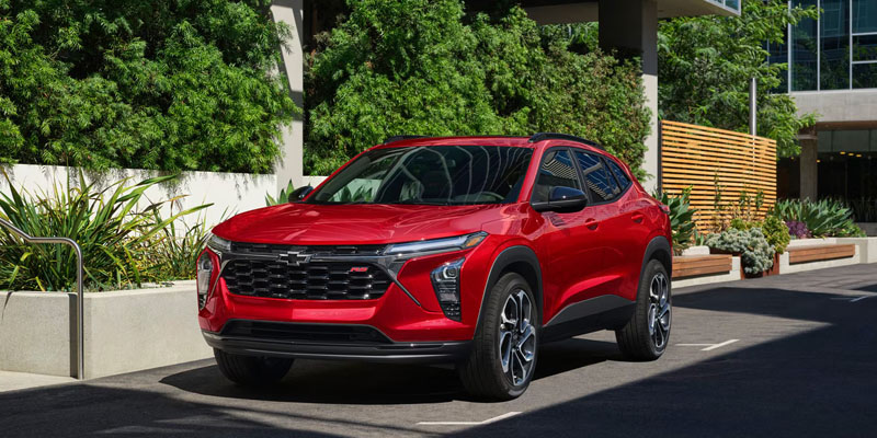 Red Chevrolet Trax SUV parked outside a modern building.