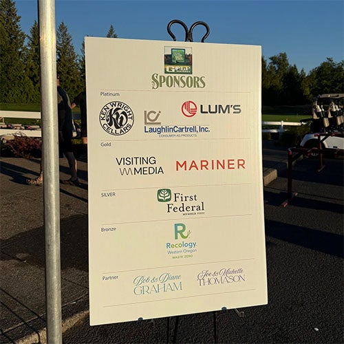 A white sign lists sponsors for an event, categorized as: Platinum, Gold, Silver, Bronze, and Partner.